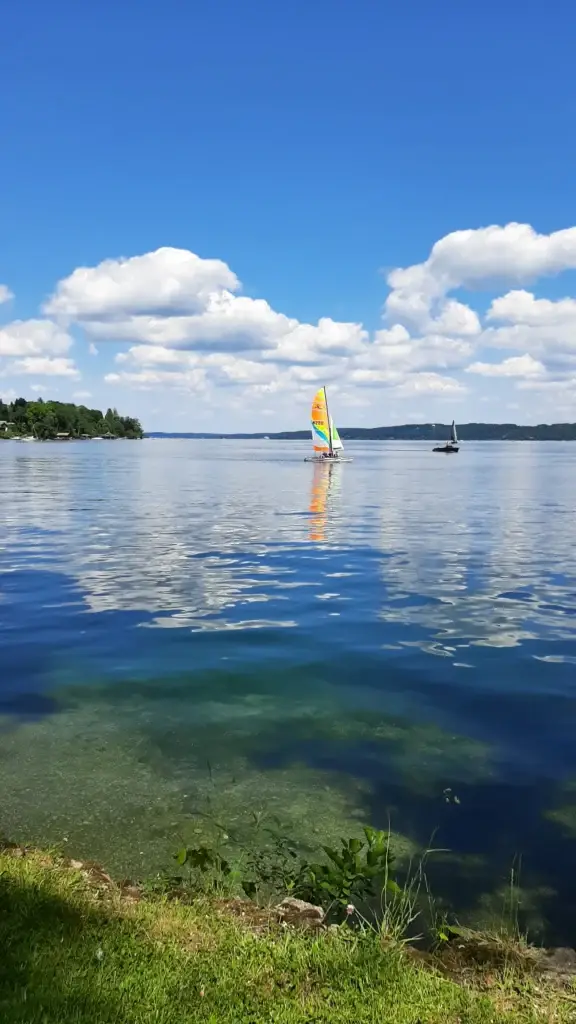Segelboot auf einem klaren See unter blauem Himmel mit Wolken